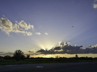 The sunset appears between clouds and trees, with an orange hue, at the end of the day on Sunday, August 13, 2023, in Florida, US. (