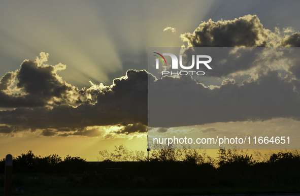 The sunset appears between clouds and trees, with an orange hue, at the end of the day on Sunday, August 13, 2023, in Florida, US. 