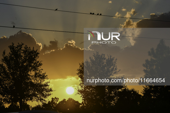 The sunset appears between clouds and trees, with an orange hue, at the end of the day on Sunday, August 13, 2023, in Florida, US. 