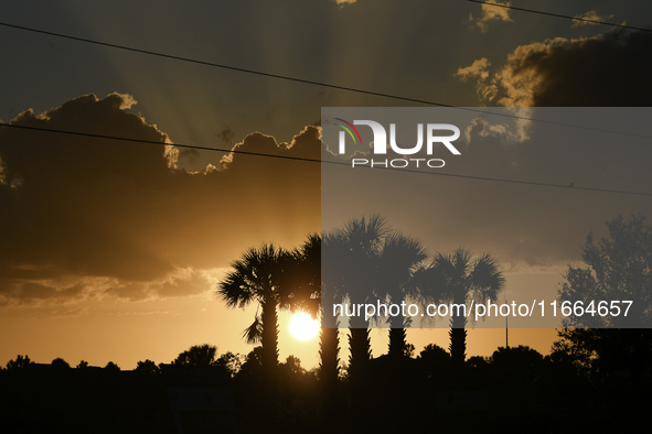 The sunset appears between clouds and trees, with an orange hue, at the end of the day on Sunday, August 13, 2023, in Florida, US. 