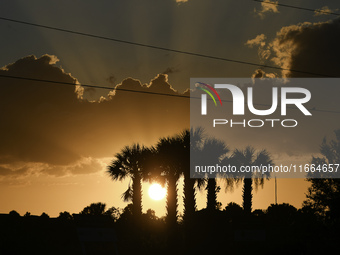 The sunset appears between clouds and trees, with an orange hue, at the end of the day on Sunday, August 13, 2023, in Florida, US. (