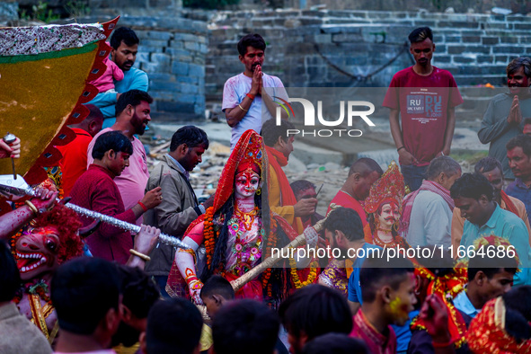 Hindu devotees immerse an idol of the Hindu goddess Durga into the Bagmati River in Kathmandu, Nepal, on October 14, 2024. In Hindu mytholog...