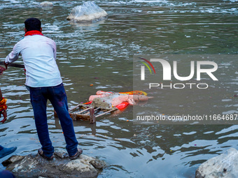 Hindu devotees immerse an idol of the Hindu goddess Durga into the Bagmati River in Kathmandu, Nepal, on October 14, 2024. In Hindu mytholog...