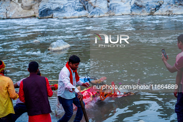 Hindu devotees immerse an idol of the Hindu goddess Durga into the Bagmati River in Kathmandu, Nepal, on October 14, 2024. In Hindu mytholog...