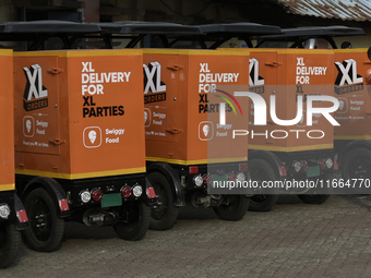 A Swiggy gig worker clicks a mobile selfie picture in front of an electric three-wheeler during a promotional event in Mumbai, India, on Oct...