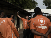 A Swiggy gig worker clicks a mobile selfie picture in front of an electric three-wheeler during a promotional event in Mumbai, India, on Oct...