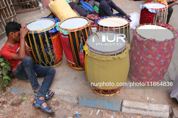 Traditional Bengali drum players, commonly known as Dhakis, gather on a footpath in North Kolkata, India, as temporary shelters and wait for...