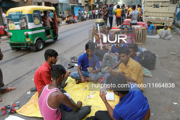 Traditional Bengali drum players in Kolkata, India, sit on the street and play cards as temporary shelters while waiting for customers for t...