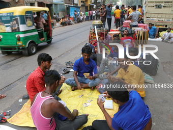 Traditional Bengali drum players in Kolkata, India, sit on the street and play cards as temporary shelters while waiting for customers for t...