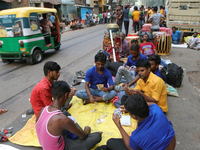 Traditional Bengali drum players in Kolkata, India, sit on the street and play cards as temporary shelters while waiting for customers for t...