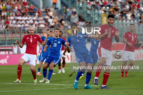 In Ta' Qali, Malta, on October 13, 2024, Luke Montebello of Malta is closely challenged by Vladislav Babogio of Moldova during the UEFA Nati...