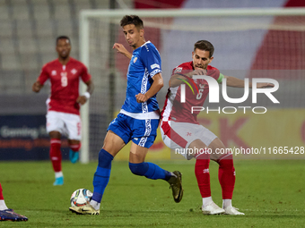 In Ta' Qali, Malta, on October 13, 2024, Mihail Caimacov of Moldova grapples for possession with Matthew Guillaumier of Malta during the UEF...