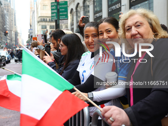 Spectators wave flags and show off Italian heritage as they march up 5th Avenue in the Columbus Day Parade in New York City, United States,...