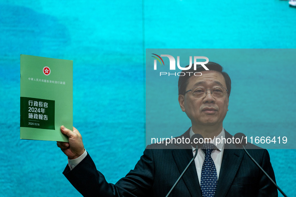 Hong Kong Chief Executive John Lee holds up a booklet of his 2024 Policy Address while speaking at a press conference before his Executive C...