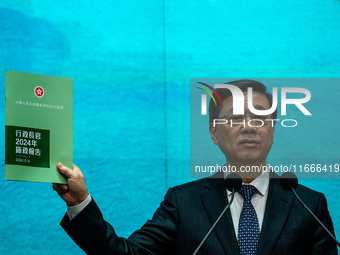 Hong Kong Chief Executive John Lee holds up a booklet of his 2024 Policy Address while speaking at a press conference before his Executive C...