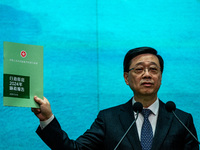 Hong Kong Chief Executive John Lee holds up a booklet of his 2024 Policy Address while speaking at a press conference before his Executive C...