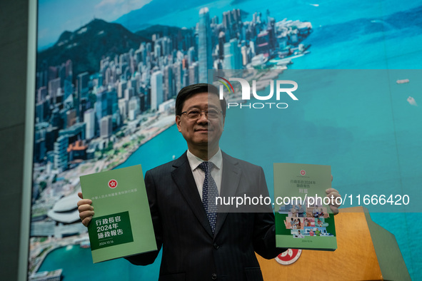 Hong Kong Chief Executive John Lee holds up booklets of his 2024 Policy Address at a press conference before his Executive Council meeting i...