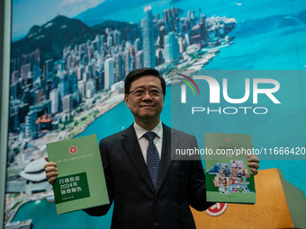 Hong Kong Chief Executive John Lee holds up booklets of his 2024 Policy Address at a press conference before his Executive Council meeting i...