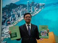 Hong Kong Chief Executive John Lee holds up booklets of his 2024 Policy Address at a press conference before his Executive Council meeting i...