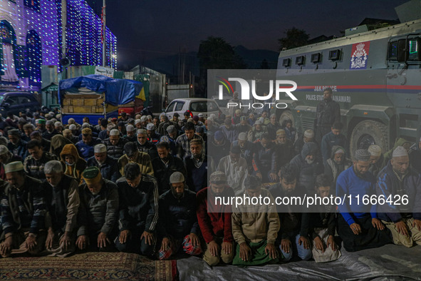 An Indian policeman stands guard as Kashmiri Muslims offer prayers at the shrine of Sheikh Abdul Qadir Jeelani, a Sufi saint, on his death a...