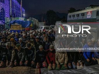 An Indian policeman stands guard as Kashmiri Muslims offer prayers at the shrine of Sheikh Abdul Qadir Jeelani, a Sufi saint, on his death a...