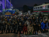 An Indian policeman stands guard as Kashmiri Muslims offer prayers at the shrine of Sheikh Abdul Qadir Jeelani, a Sufi saint, on his death a...