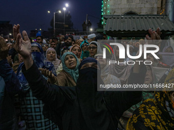 Kashmiri Muslim women raise their arms in prayer upon seeing a relic of Sheikh Abdul Qadir Jeelani, a Sufi saint, on his death anniversary o...