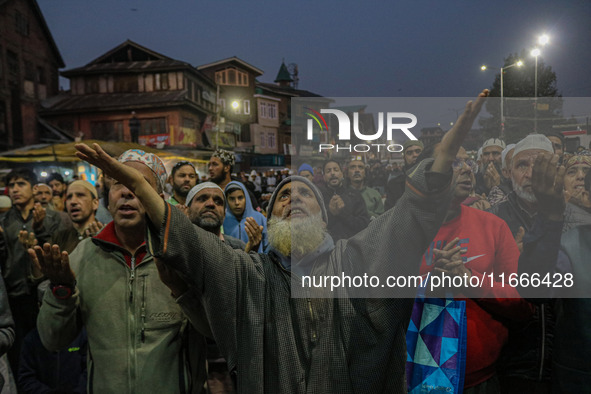 Kashmiri Muslims raise their arms in prayer upon seeing a relic of Sheikh Abdul Qadir Jeelani, a Sufi saint, on his death anniversary outsid...