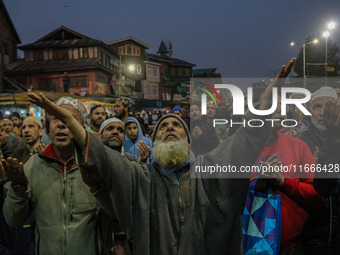 Kashmiri Muslims raise their arms in prayer upon seeing a relic of Sheikh Abdul Qadir Jeelani, a Sufi saint, on his death anniversary outsid...