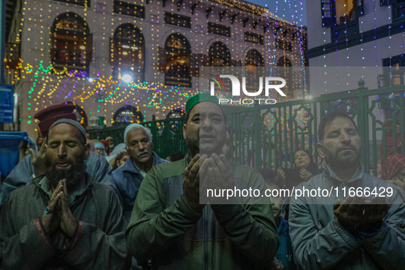 Kashmiri Muslims raise their arms in prayer upon seeing a relic of Sheikh Abdul Qadir Jeelani, a Sufi saint, on his death anniversary outsid...