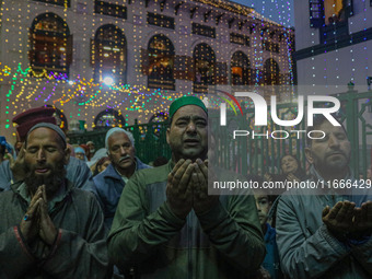 Kashmiri Muslims raise their arms in prayer upon seeing a relic of Sheikh Abdul Qadir Jeelani, a Sufi saint, on his death anniversary outsid...