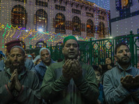 Kashmiri Muslims raise their arms in prayer upon seeing a relic of Sheikh Abdul Qadir Jeelani, a Sufi saint, on his death anniversary outsid...