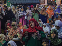 A Kashmiri Muslim woman prays upon seeing a relic of Sheikh Abdul Qadir Jeelani, a Sufi saint, on his death anniversary outside his shrine i...