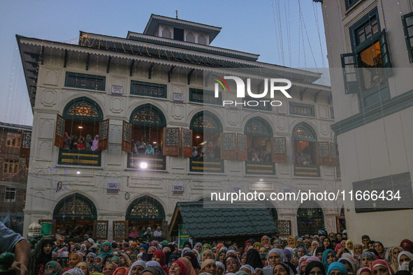 Kashmiri Muslim women raise their arms in prayer upon seeing a relic of Sheikh Abdul Qadir Jeelani, a Sufi saint, on his death anniversary o...