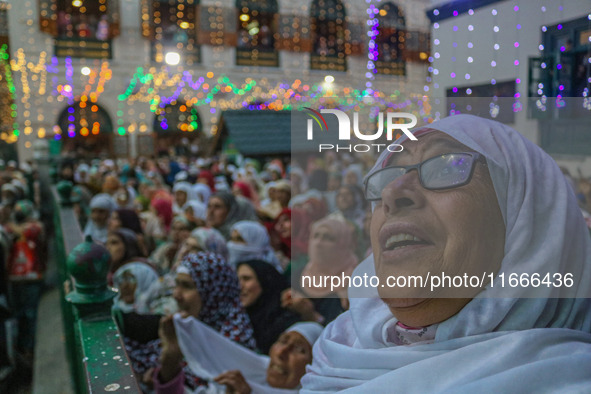 A Kashmiri Muslim woman prays upon seeing a relic of Sheikh Abdul Qadir Jeelani, a Sufi saint, on his death anniversary outside his shrine i...