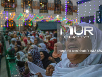 A Kashmiri Muslim woman prays upon seeing a relic of Sheikh Abdul Qadir Jeelani, a Sufi saint, on his death anniversary outside his shrine i...