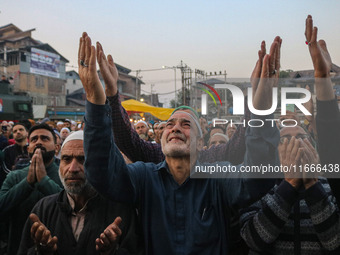 Kashmiri Muslims raise their arms in prayer upon seeing a relic of Sheikh Abdul Qadir Jeelani, a Sufi saint, on his death anniversary outsid...