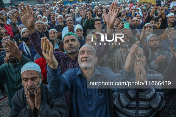 Kashmiri Muslims raise their arms in prayer upon seeing a relic of Sheikh Abdul Qadir Jeelani, a Sufi saint, on his death anniversary outsid...