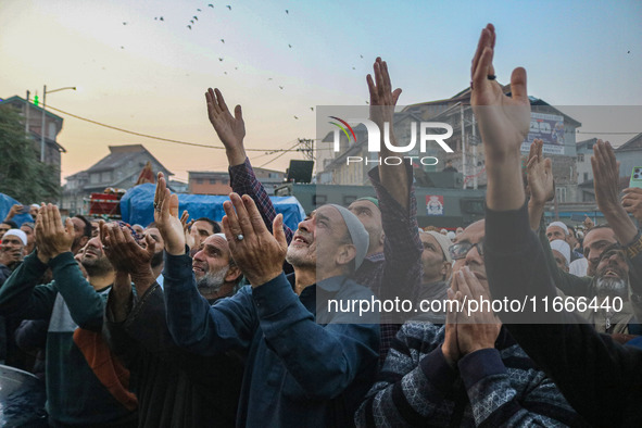 Kashmiri Muslims raise their arms in prayer upon seeing a relic of Sheikh Abdul Qadir Jeelani, a Sufi saint, on his death anniversary outsid...