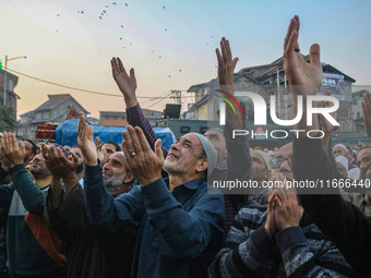 Kashmiri Muslims raise their arms in prayer upon seeing a relic of Sheikh Abdul Qadir Jeelani, a Sufi saint, on his death anniversary outsid...