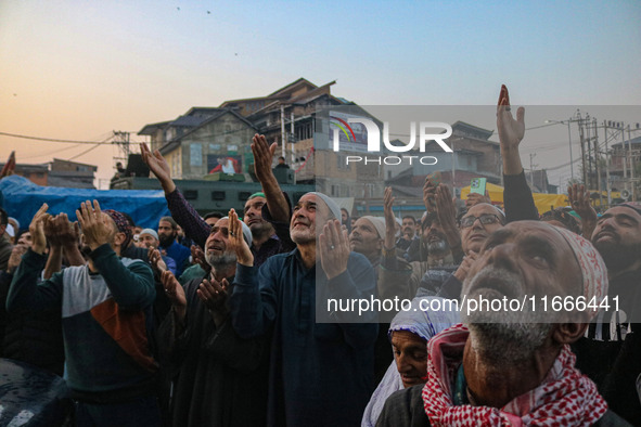 Kashmiri Muslims raise their arms in prayer upon seeing a relic of Sheikh Abdul Qadir Jeelani, a Sufi saint, on his death anniversary outsid...