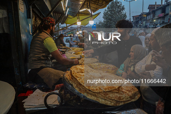 Kashmiri Muslims buy local snacks from a vendor outside the shrine of Sheikh Abdul Qadir Jeelani, a Sufi saint, in Srinagar, Jammu and Kashm...