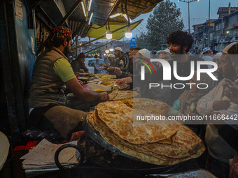 Kashmiri Muslims buy local snacks from a vendor outside the shrine of Sheikh Abdul Qadir Jeelani, a Sufi saint, in Srinagar, Jammu and Kashm...