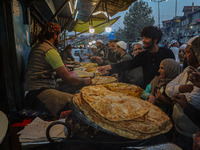 Kashmiri Muslims buy local snacks from a vendor outside the shrine of Sheikh Abdul Qadir Jeelani, a Sufi saint, in Srinagar, Jammu and Kashm...