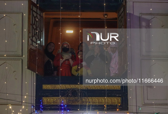 Kashmiri Muslim women raise their arms in prayer upon seeing a relic of Sheikh Abdul Qadir Jeelani, a Sufi saint, on his death anniversary o...