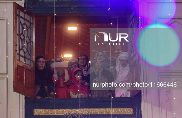 Kashmiri Muslim women raise their arms in prayer upon seeing a relic of Sheikh Abdul Qadir Jeelani, a Sufi saint, on his death anniversary o...