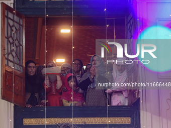 Kashmiri Muslim women raise their arms in prayer upon seeing a relic of Sheikh Abdul Qadir Jeelani, a Sufi saint, on his death anniversary o...