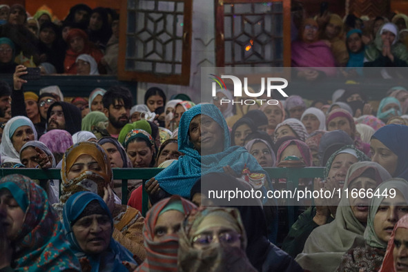 Kashmiri Muslim women raise their arms in prayer upon seeing a relic of Sheikh Abdul Qadir Jeelani, a Sufi saint, on his death anniversary o...