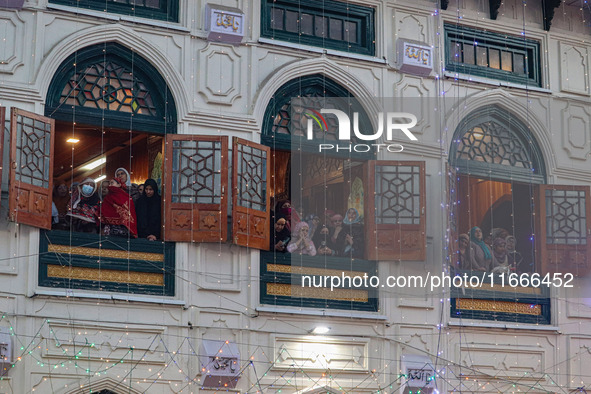 Kashmiri Muslim women raise their arms in prayer upon seeing a relic of Sheikh Abdul Qadir Jeelani, a Sufi saint, on his death anniversary o...