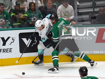 Miro Heiskanen #4 of the Dallas Stars and Andre Burakovsky #95 of the Seattle Kraken skate on the ice while battling for the puck during the...